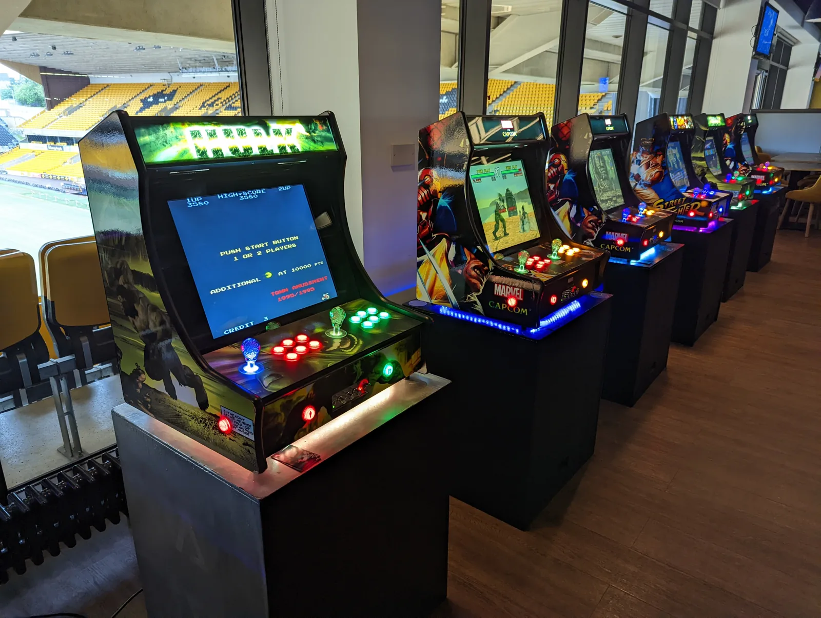 Arcade Party cabinets lined up beside stadium windows at an event