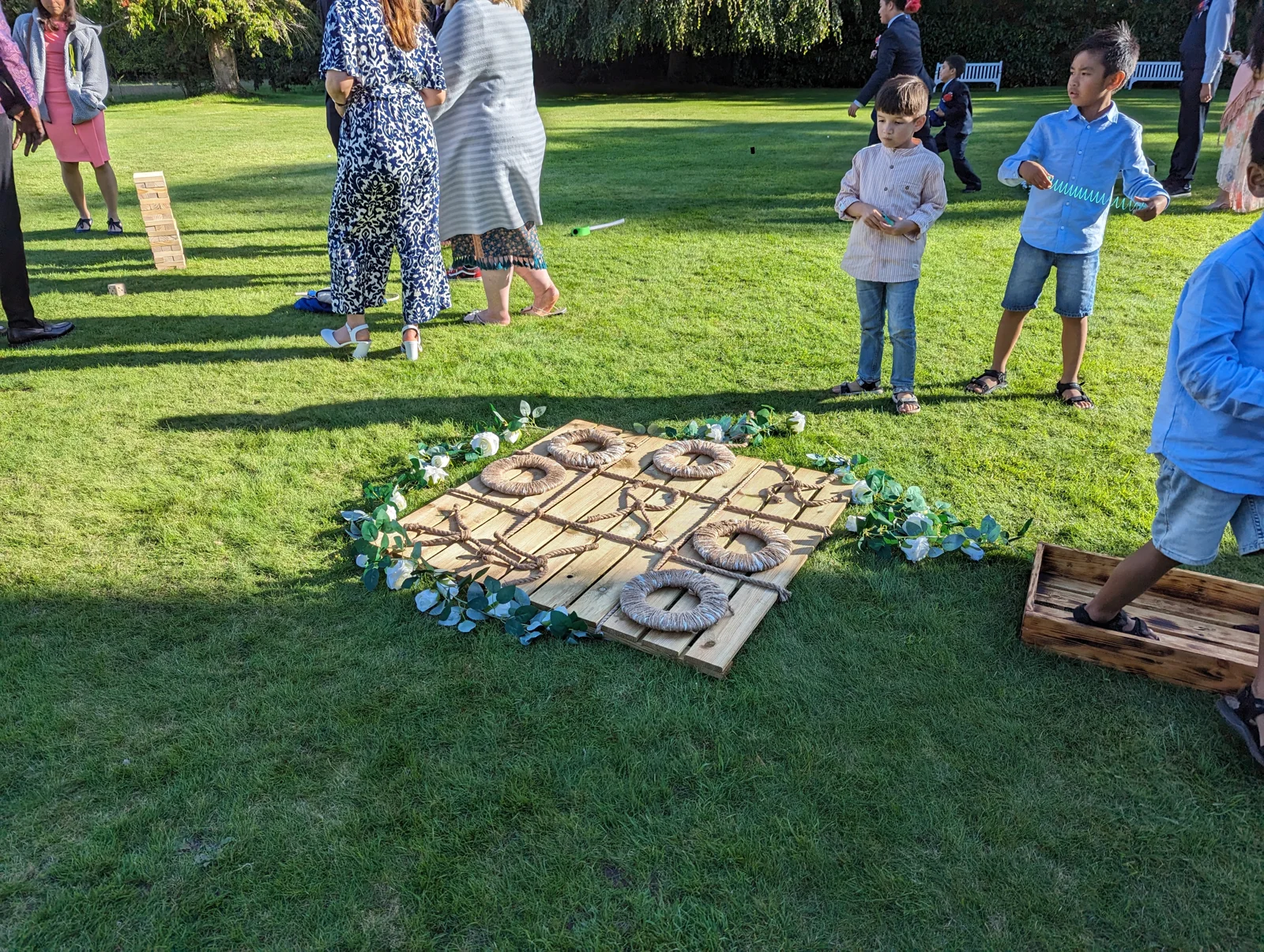 Guests gathered around rustic noughts and crosses on a lawn