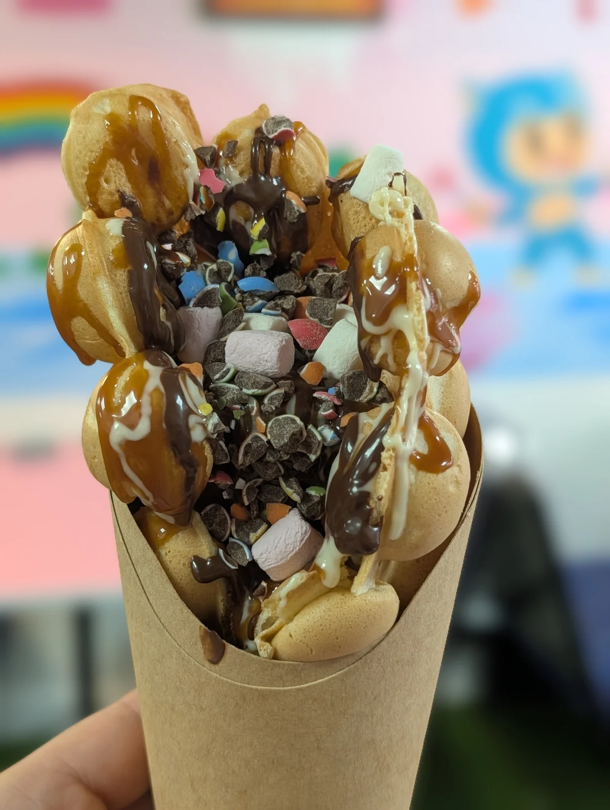 Loaded bubble waffle with chocolate drizzle and colourful toppings at Arcade Sweets