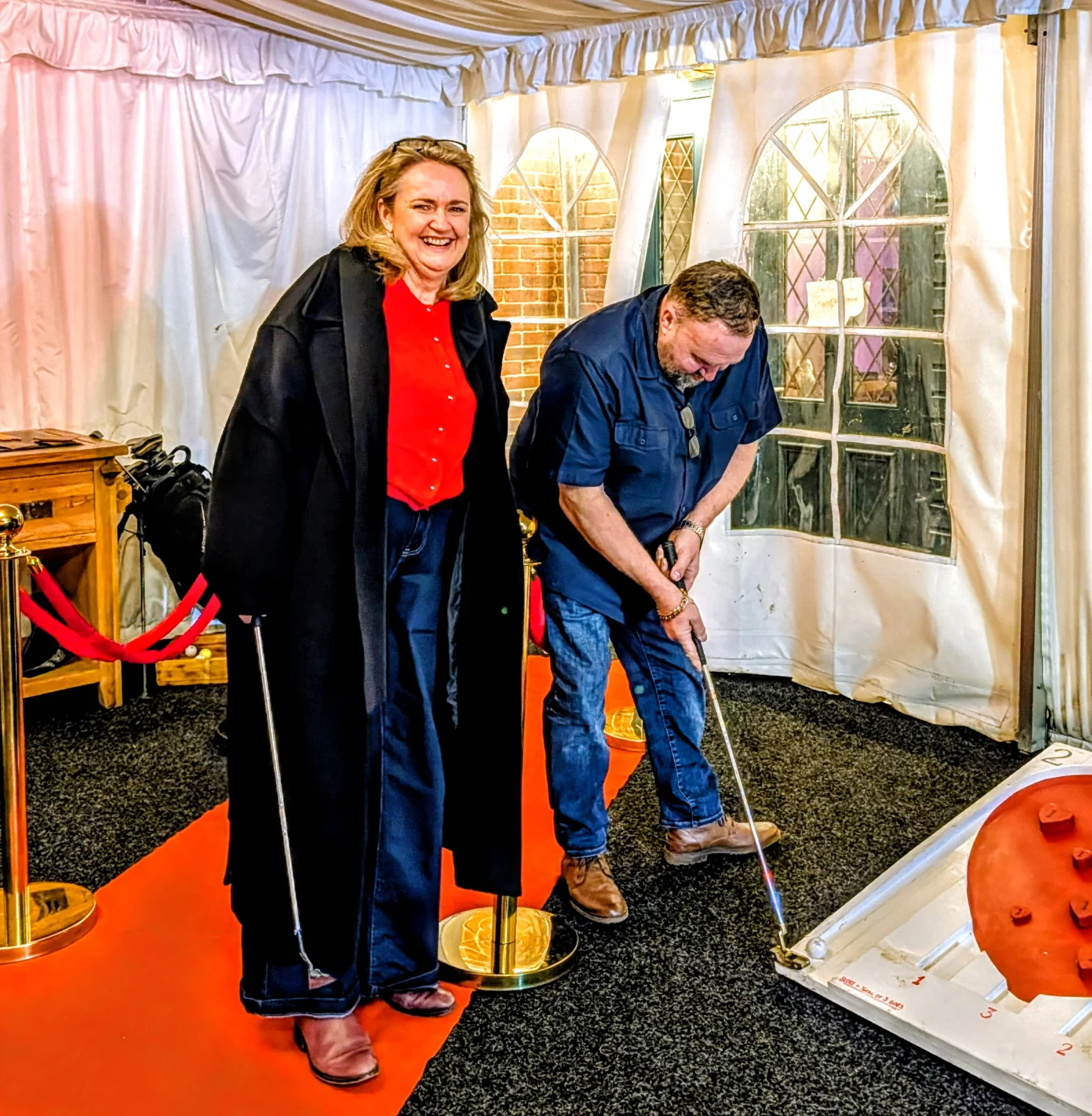 Guests laughing and playing mini golf in a marquee