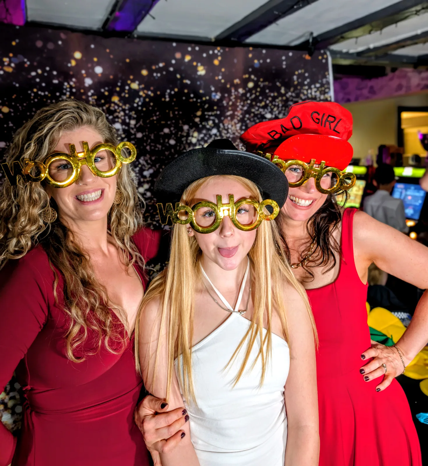 Three guests laughing in photobooth glasses and colourful hats