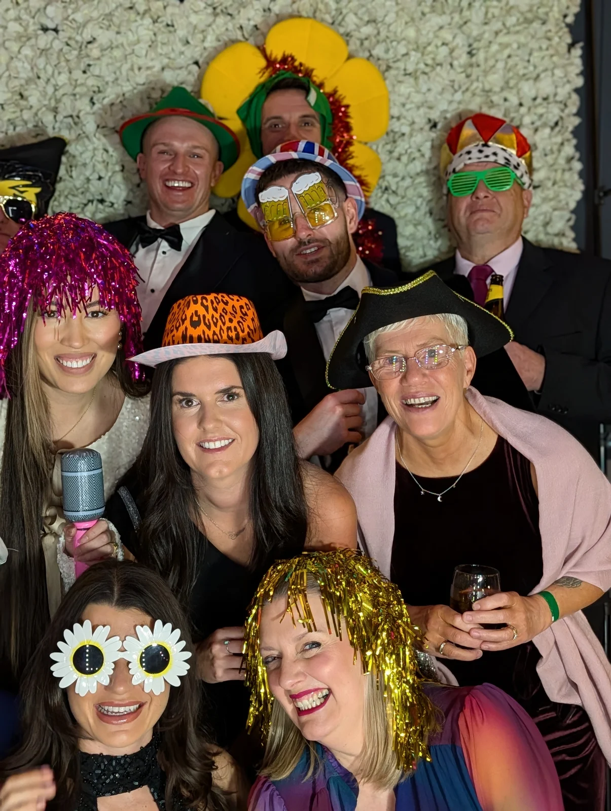 Party guests smiling together in colourful hats and playful photobooth props