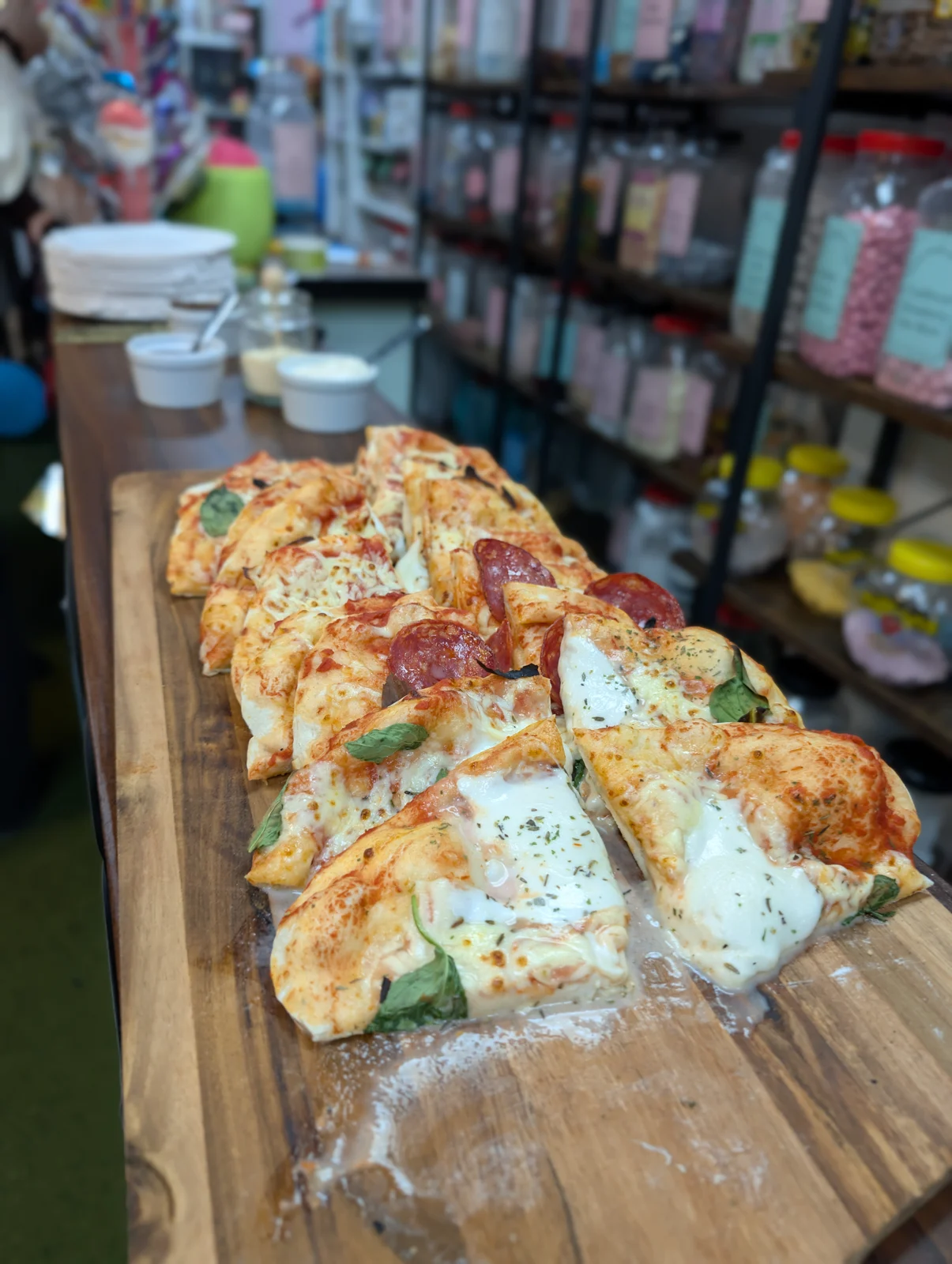 Pizzas with assorted toppings on a wooden serving board at Arcade Sweets