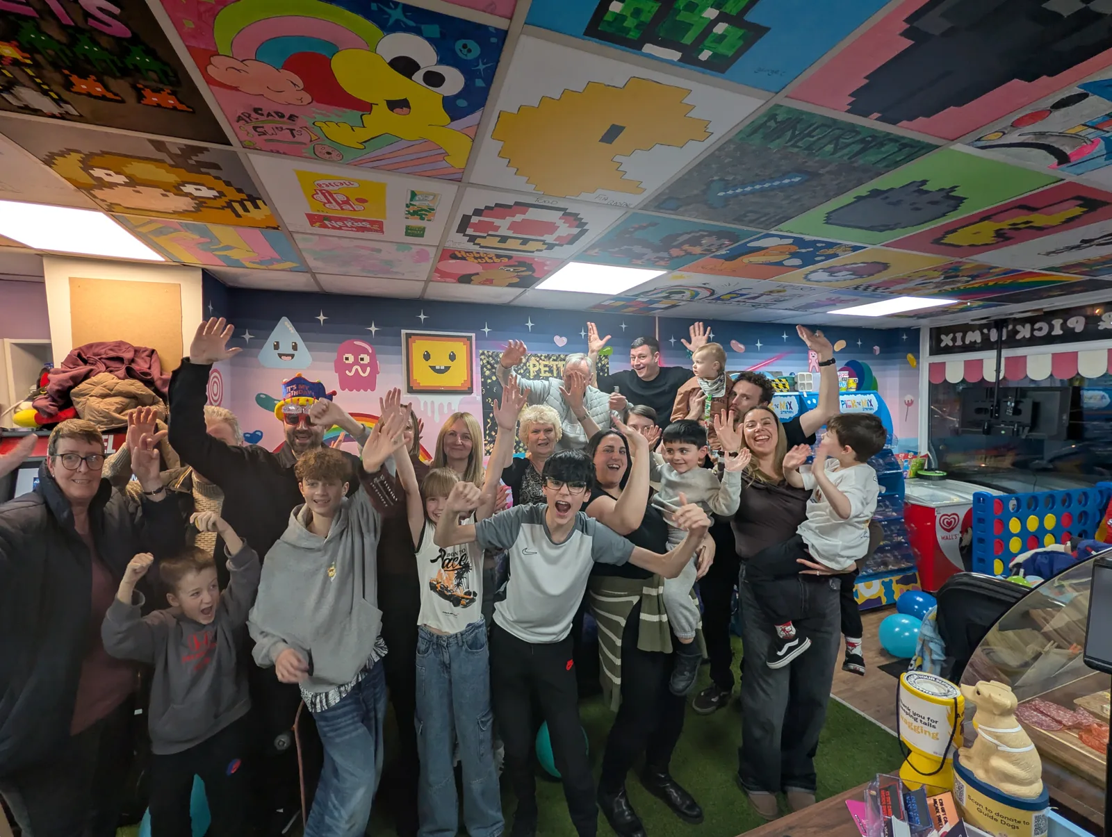 A large group celebrating together inside the colourful Arcade Sweets shop
