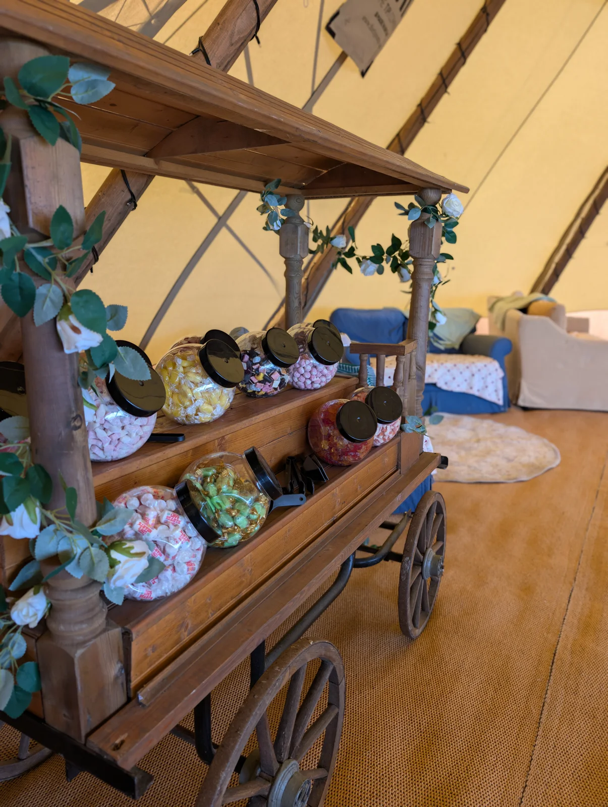 Rustic wooden sweet cart with jars of sweets and floral decoration