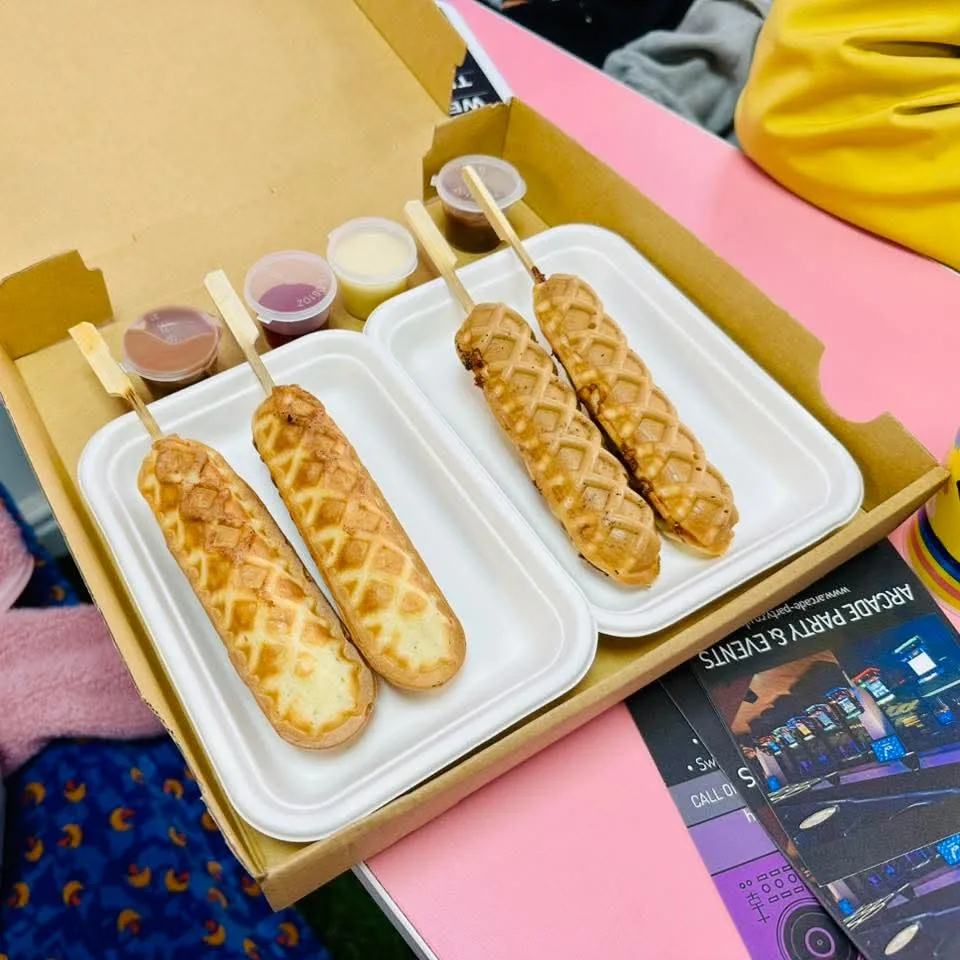 Waffles on sticks served in trays with separate pots of toppings at Arcade Sweets